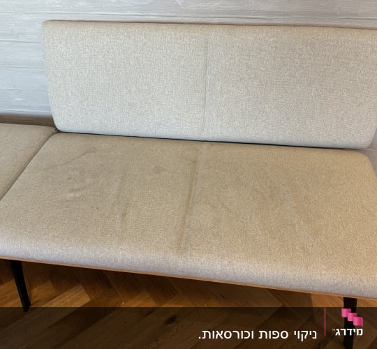 כתמים על ספה בהירה עם רגלי מתכת שחורות